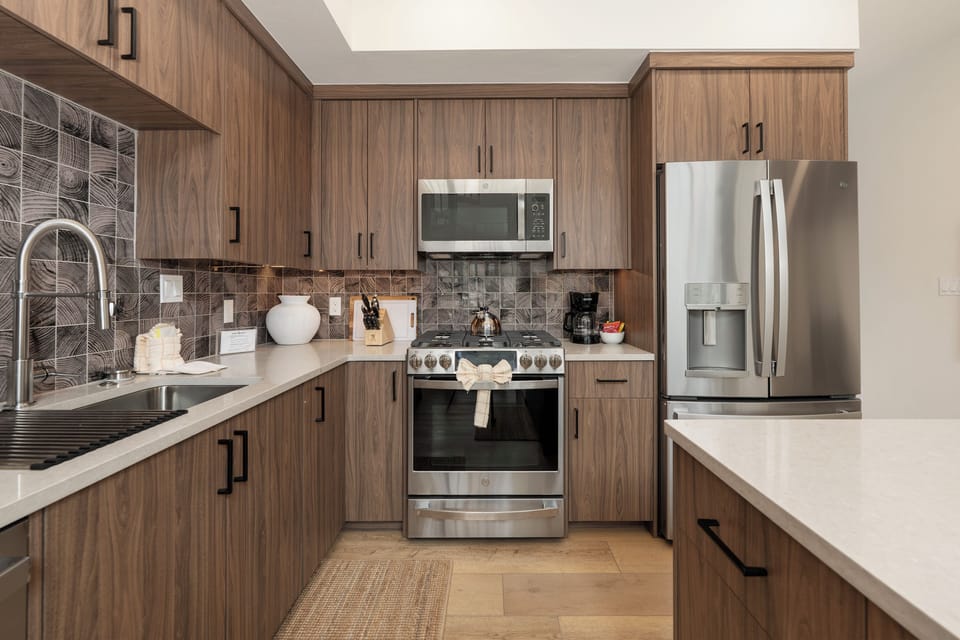 Your fully equipped modern kitchen awaits with sleek wood cabinets, stainless steel appliances, and bright natural light from the skylight above.