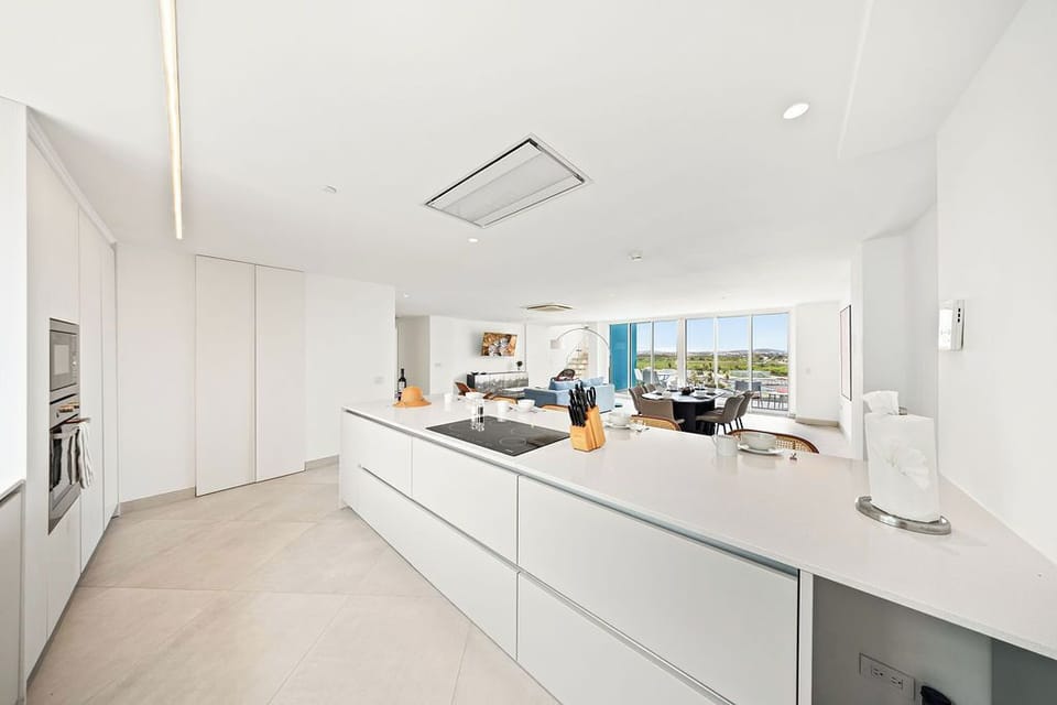 Step into your sleek, open-plan retreat where crisp white finishes and stunning water views create a serene backdrop for your stay. Enjoy cooking in the modern kitchen with top-tier appliances, then unwind in the bright living space bathed in natural light