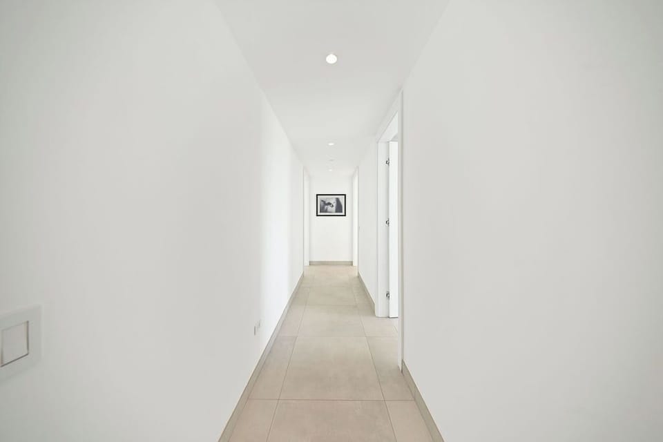 A bright, clean hallway connects the different spaces in your vacation home, with a framed artwork adding a welcoming touch as you move through the property.