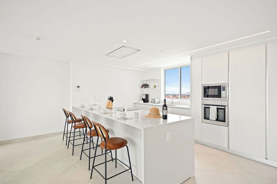 Your sleek kitchen invites morning coffee at the island, with built-in appliances, modern fixtures, and abundant natural light to inspire your culinary adventures.