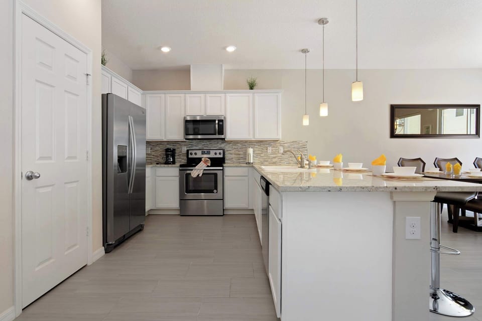Chef-ready, modern kitchen featuring stainless appliances, mosaic backsplash, and a spacious island with seating for four-perfect for shared meals and conversation.