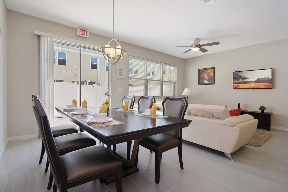 Sunny open-plan dining and lounge-seats 6-8 under a chic globe pendant, with sliding doors to the patio and a cozy sofa nearby.