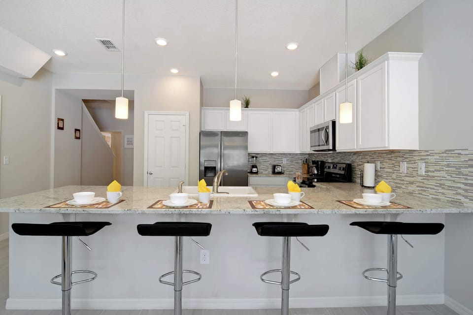 Gather at the sleek breakfast bar-granite counters, pendant lights, and stainless appliances set a clean, modern tone for easy meals.