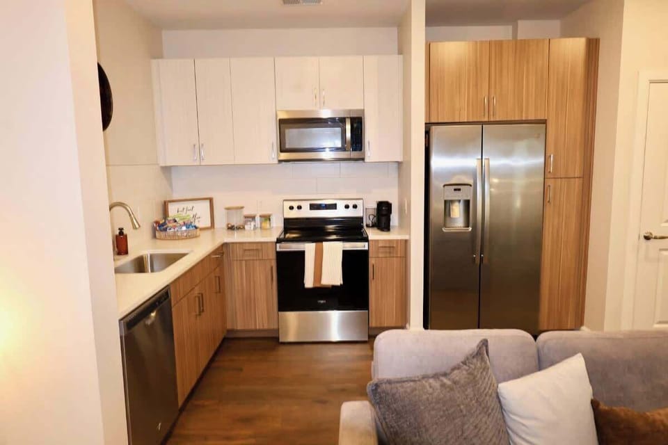 - Modern kitchen with stainless appliances and bright lighting  
- Fully equipped for cooking during extended stays  
- Warm wood cabinets create a clean comfortable feel  
