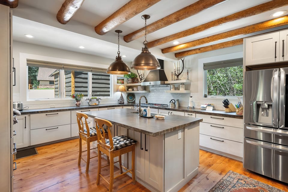 - Spacious kitchen island with bar stools perfect for casual dining   - Rustic beams and pendant lighting highlight cabin style atmosphere   - Open floor plan makes this space ideal for cooking and gathering