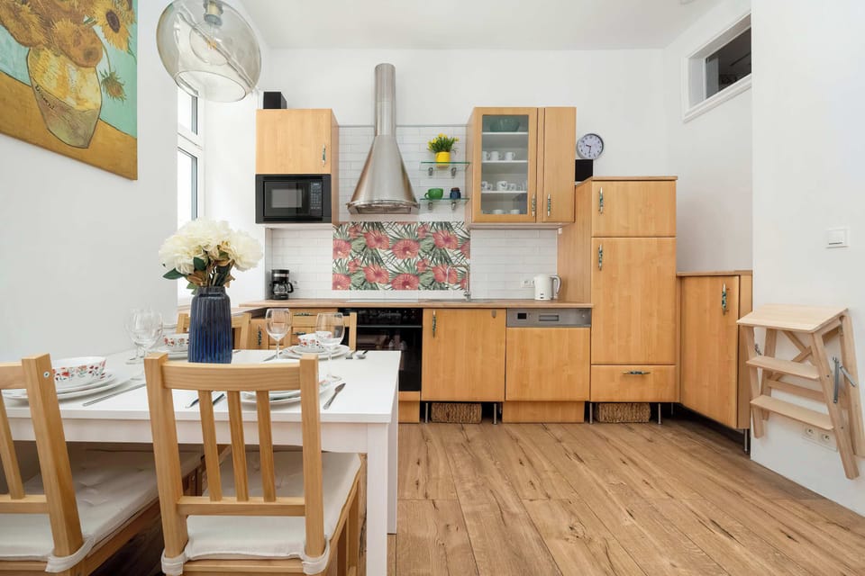 A compact dining area adjacent to a fully equipped kitchen with light wood cabinets and white walls.