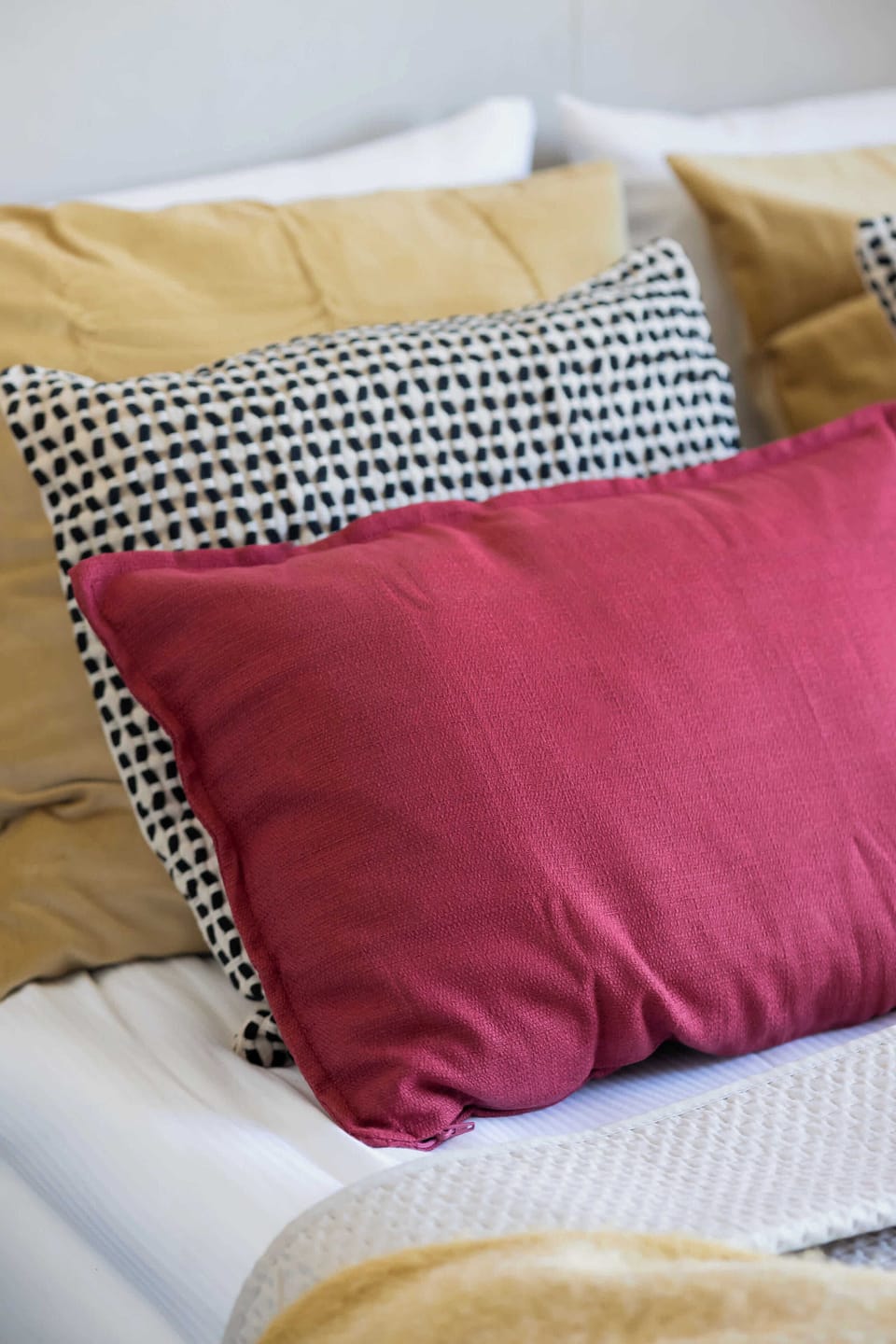 A colorful close-up of two pillows on a white bed. The vibrant pink and yellow cushions add playful charm.