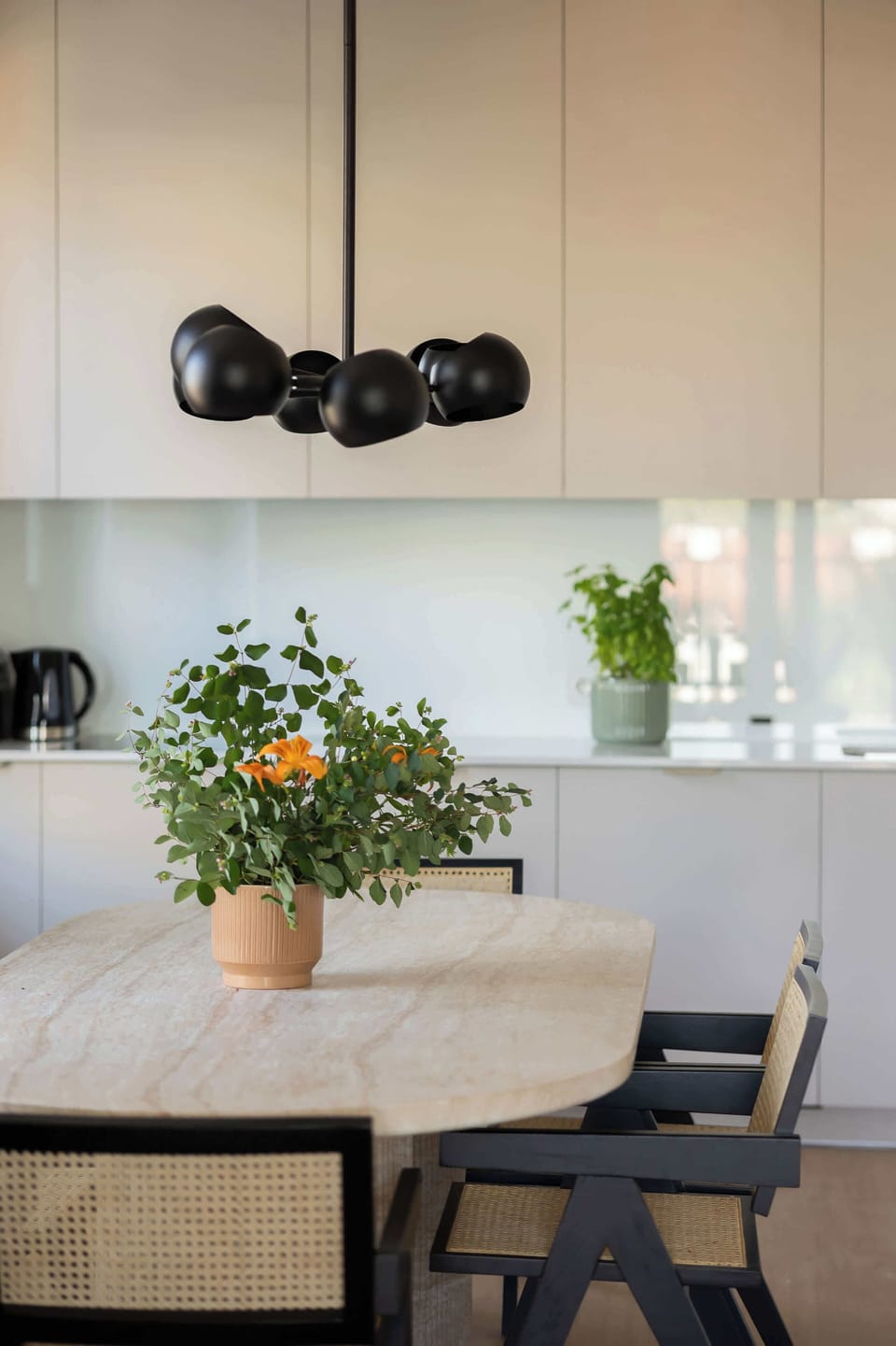 A kitchenette with white cabinetry and a clean design. A coffee maker and kettle sit on the black countertop.
