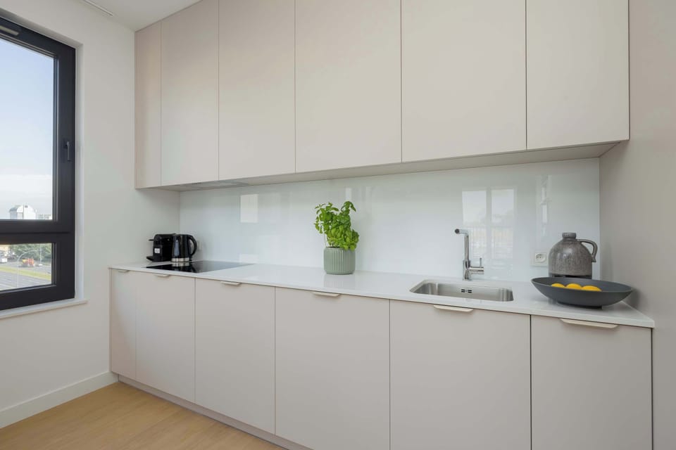 A sleek kitchen area with white cabinets and built-in appliances. The minimalist aesthetic emphasizes functionality.