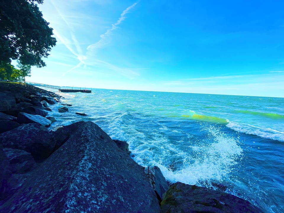 Peaceful lakefront views just steps from the patio—waves roll in over smooth rocks as the open sky stretches endlessly across the horizon.