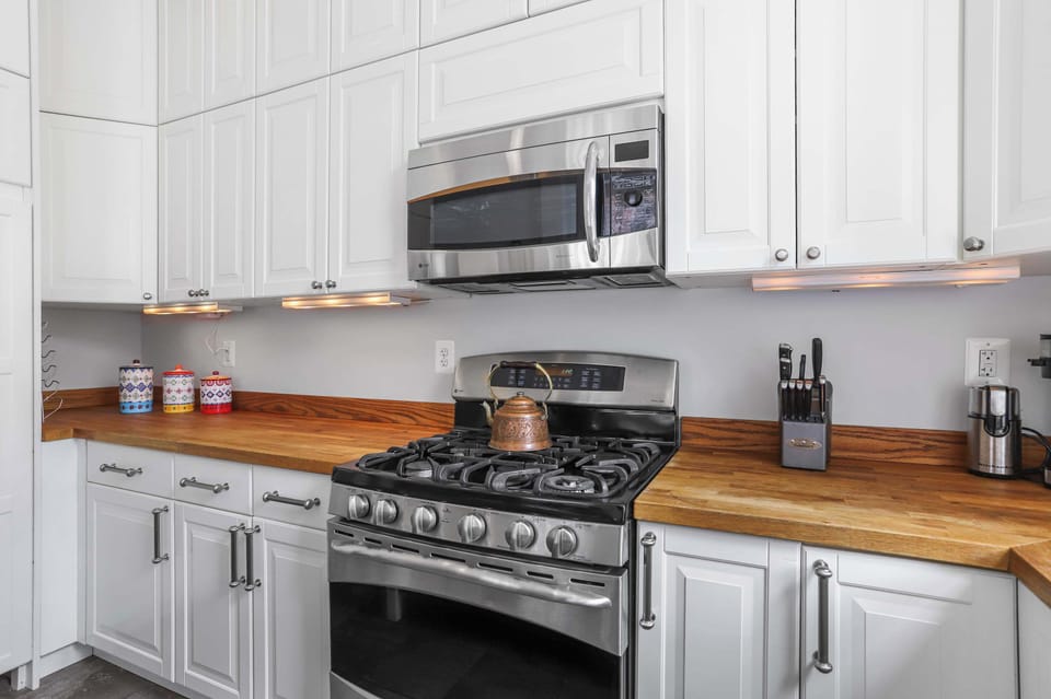 Kitchen with a view of wooden finish countertop, steel appliance finish oven and microwave.