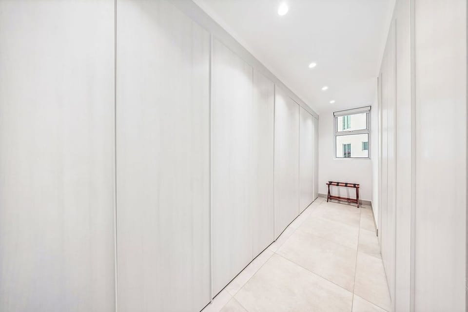 Bright, minimalist hallway offers serene simplicity with clean lines, recessed lighting, and ample wardrobe storage—perfect for keeping your space organized and clutter-free during your stay.