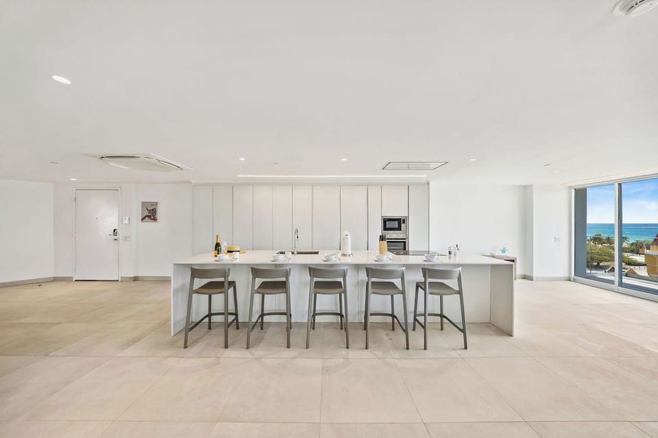 Gather around this sleek island kitchen with ocean views—your perfect spot for morning coffee or evening cocktails with friends.