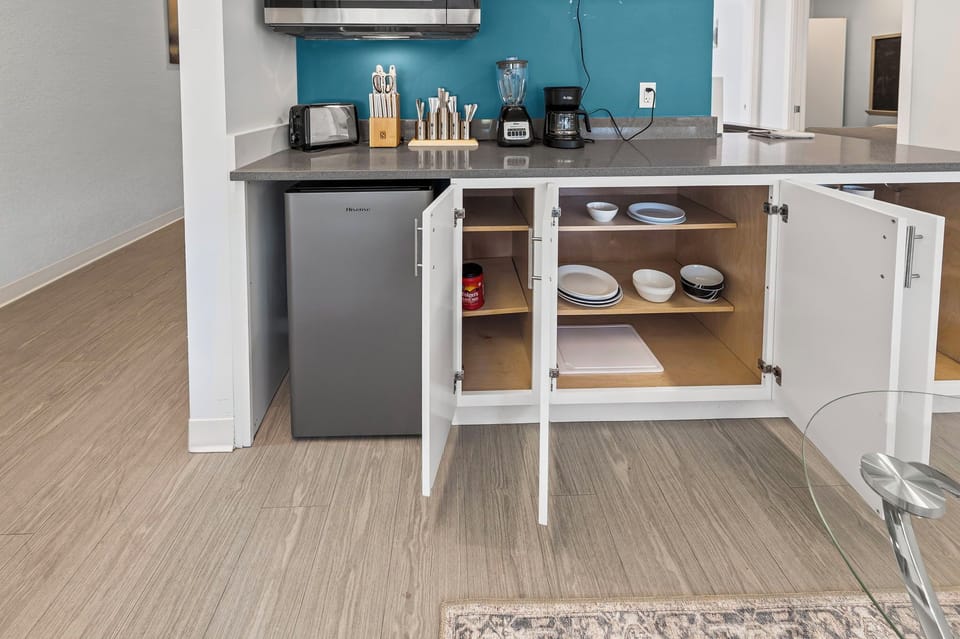 Fully stocked kitchenette with mini fridge, toaster, blender, and cookware.