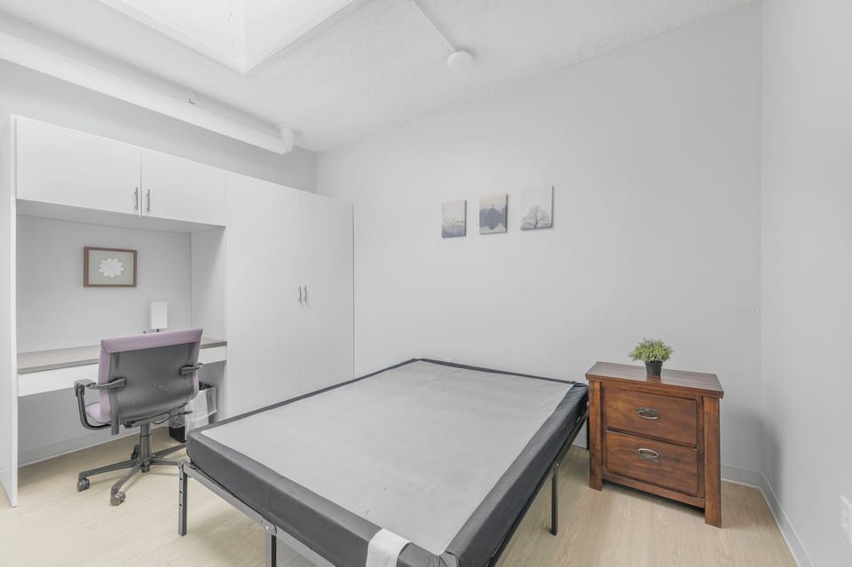 Clean room w/ queen bed, desk, lamp & storage—quiet space for work or rest.