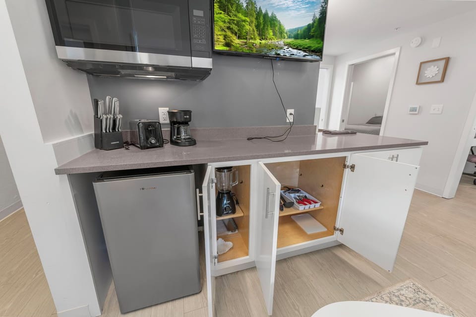Kitchenette w/ fridge, microwave, coffee maker & cookware—meal-ready space.