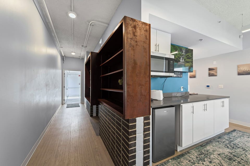 Modern entry w/ kitchenette, cozy lounge & wood-brick shelving near campus.