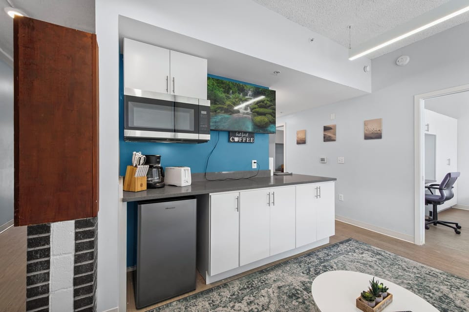 Modern kitchenette w/ fridge, microwave, coffee bar & TV—bright & cozy stay.