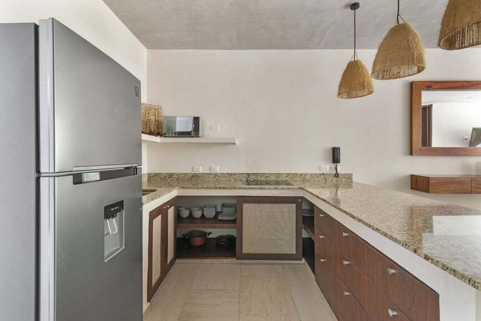 Modern kitchen with granite counters, fridge, and stylish lighting.