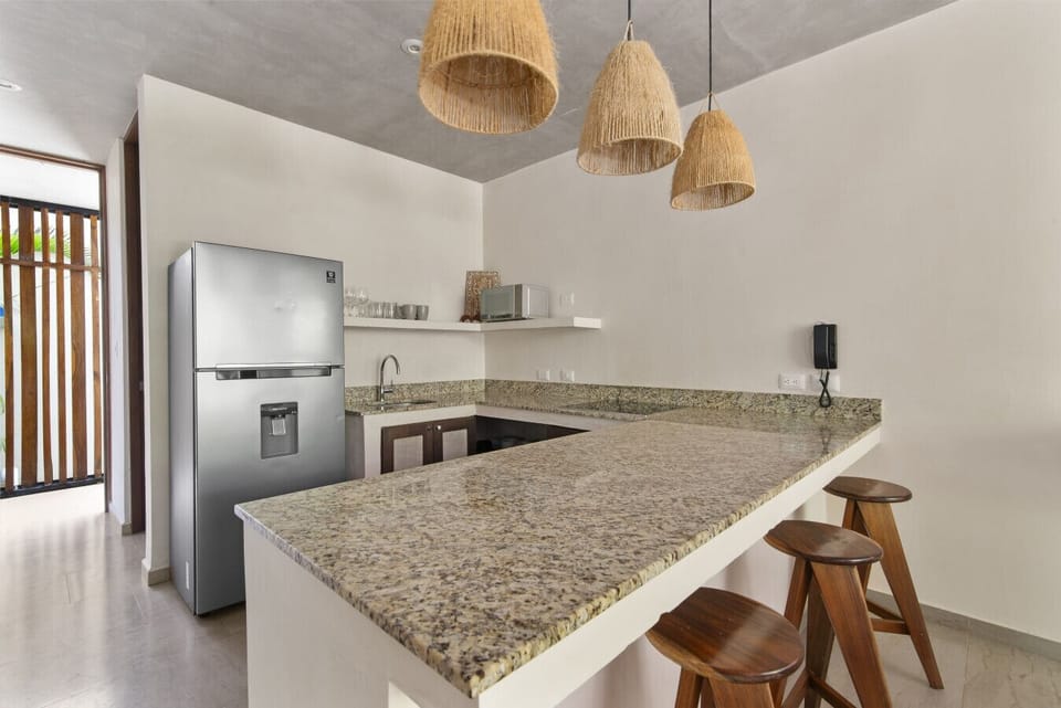 Modern kitchen with granite counters, appliances, and cozy wooden stools.