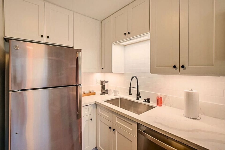 Spacious sink area with under-cabinet lighting and sleek black fixtures.