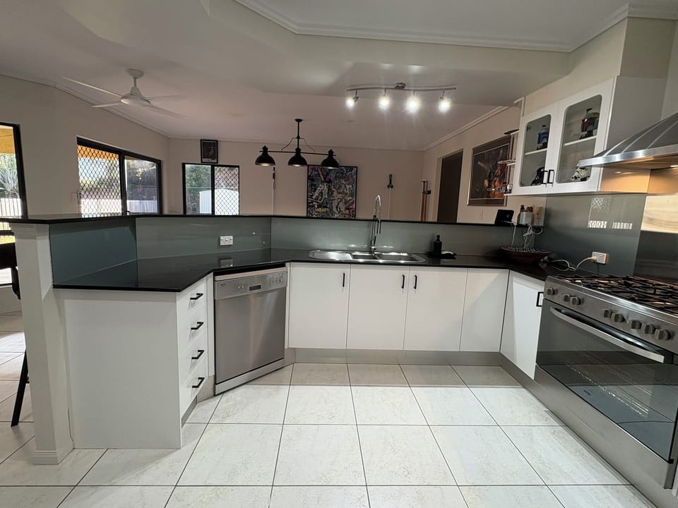 Kitchen with stone benchtops, 900mm wide stainless-steel oven and gas cooktop.