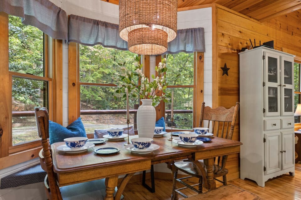 Rustic Dining Nook | Wood Table with Blue and White Dishes, Cozy Cabin Ambiance, and Nature Views