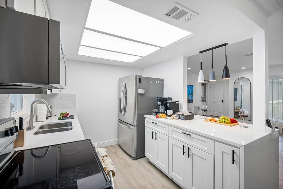 This modern kitchen features clean white cabinetry, quartz countertops, and stainless steel appliances for a fresh, polished look.