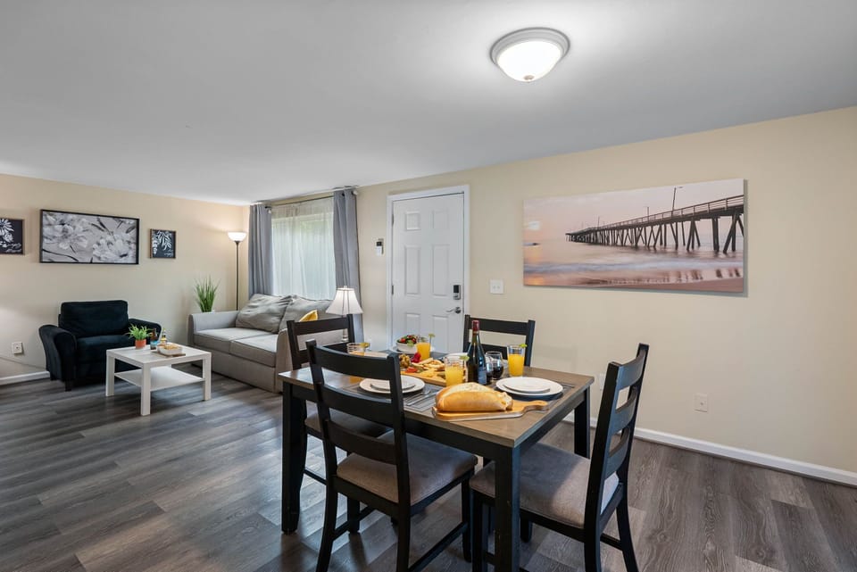 Featuring a solid wood dining table with a natural finish and four cushioned chairs in a sleek dark frame.