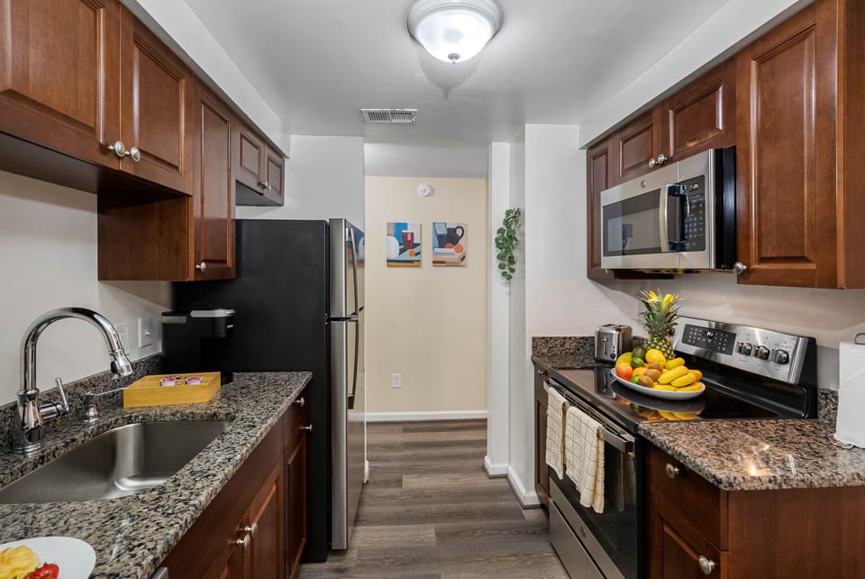 Designed for both convenience and comfort, this space features rich wooden cabinetry paired with sleek granite countertops offering generous prep space for all your culinary needs.