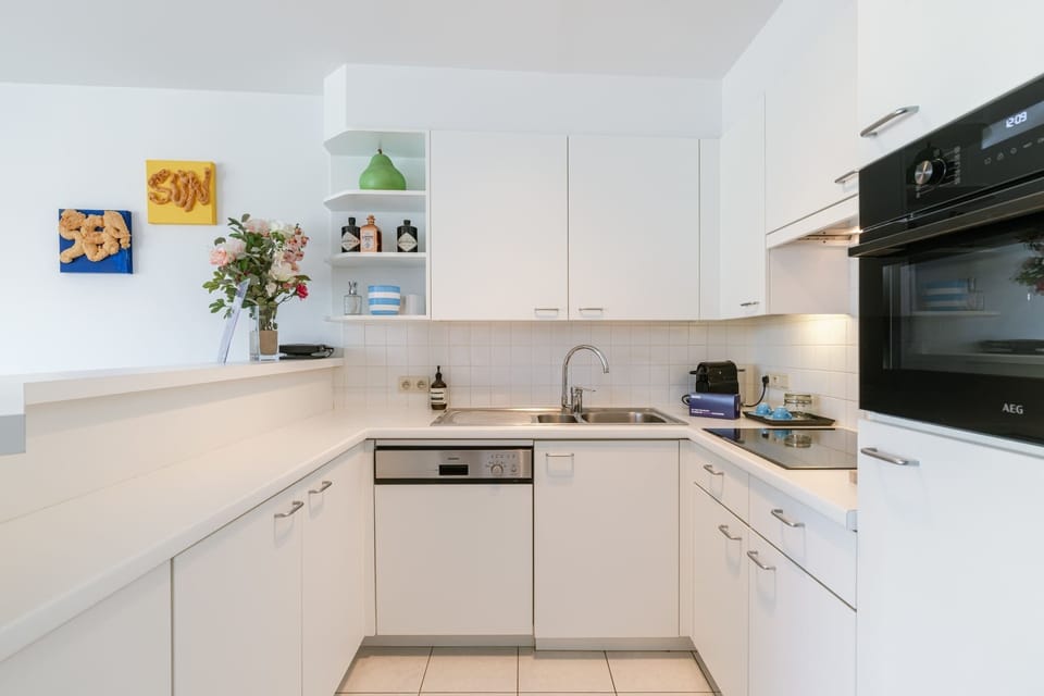 White kitchen with built-in oven, open shelving and plants