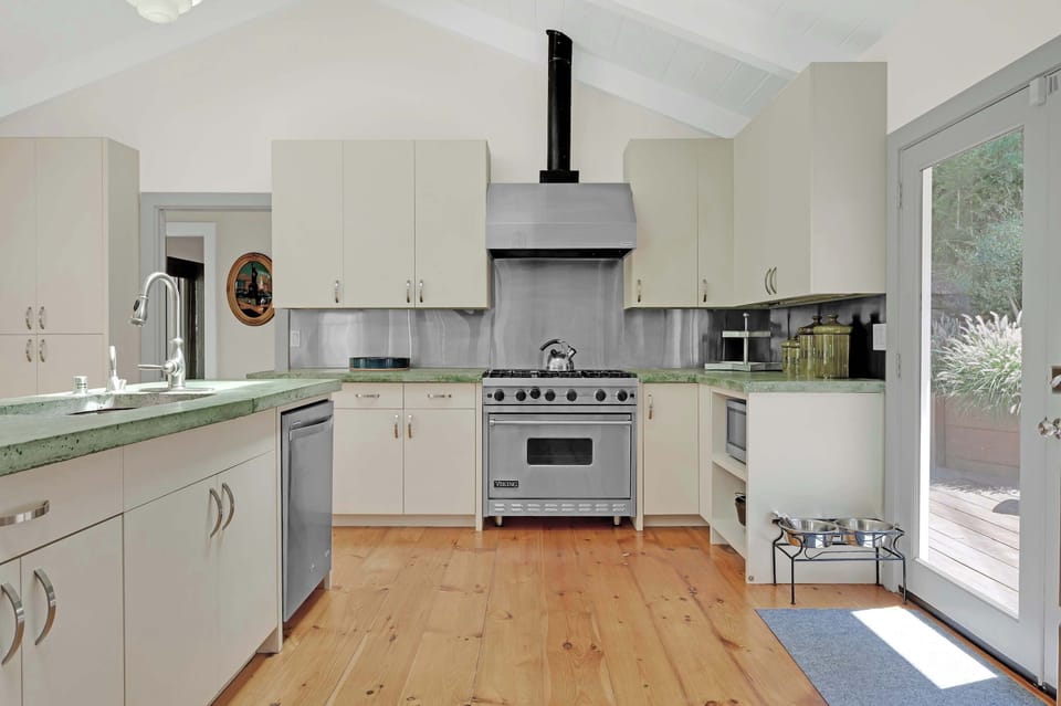 Custom concrete countertop kitchen with high-end appliances and picture windows framing redwood treetops — cook while the view does the heavy lifting