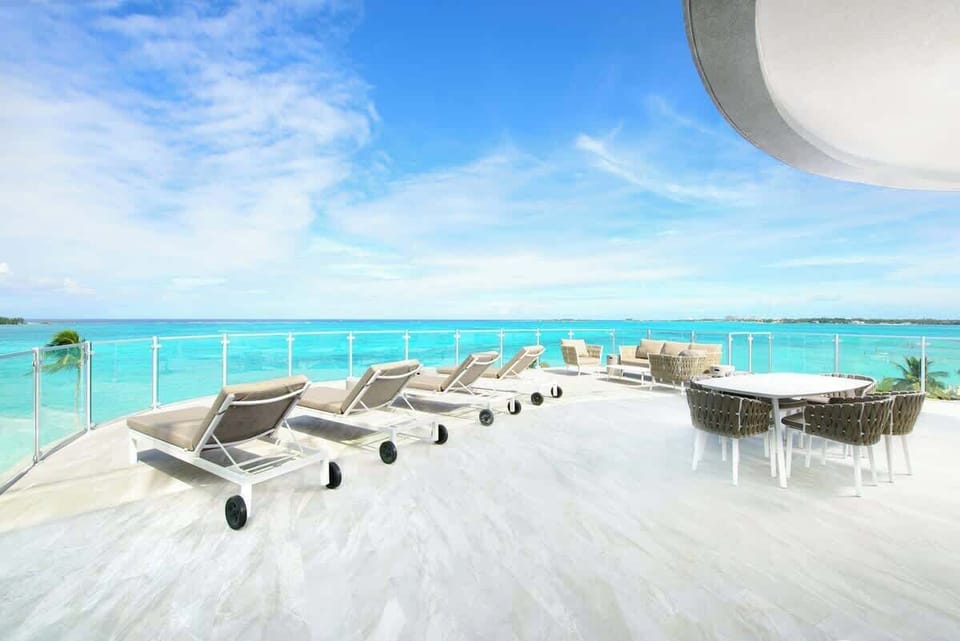 Spacious and private ocean front balcony with dining table, sun loungers and seating area
