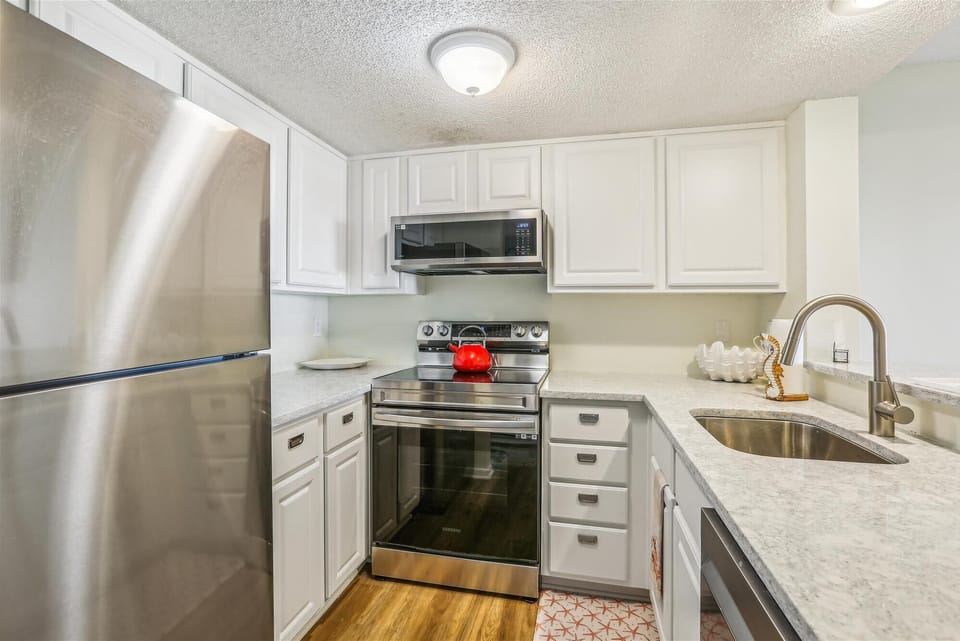- Kitchen features stainless steel fridge, oven and microwave with bright countertops  
- Updated design with plenty of cabinet space for easy meal prep during your stay  
- Functional and stylish cooking area  