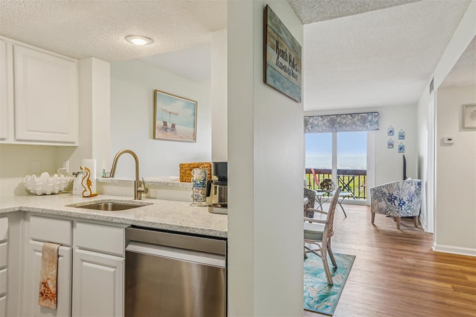 - Kitchen with modern appliances and white cabinets leads into dining area with balcony view  
- Open layout connects cooking and living space filled with natural light  
- Perfect spot for family meals together