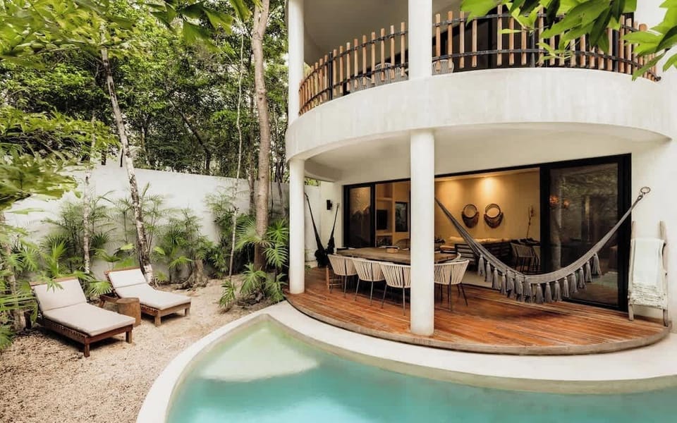 Outdoor terrace with macrame hammock, sunlounger, and surrounding jungle greenery.