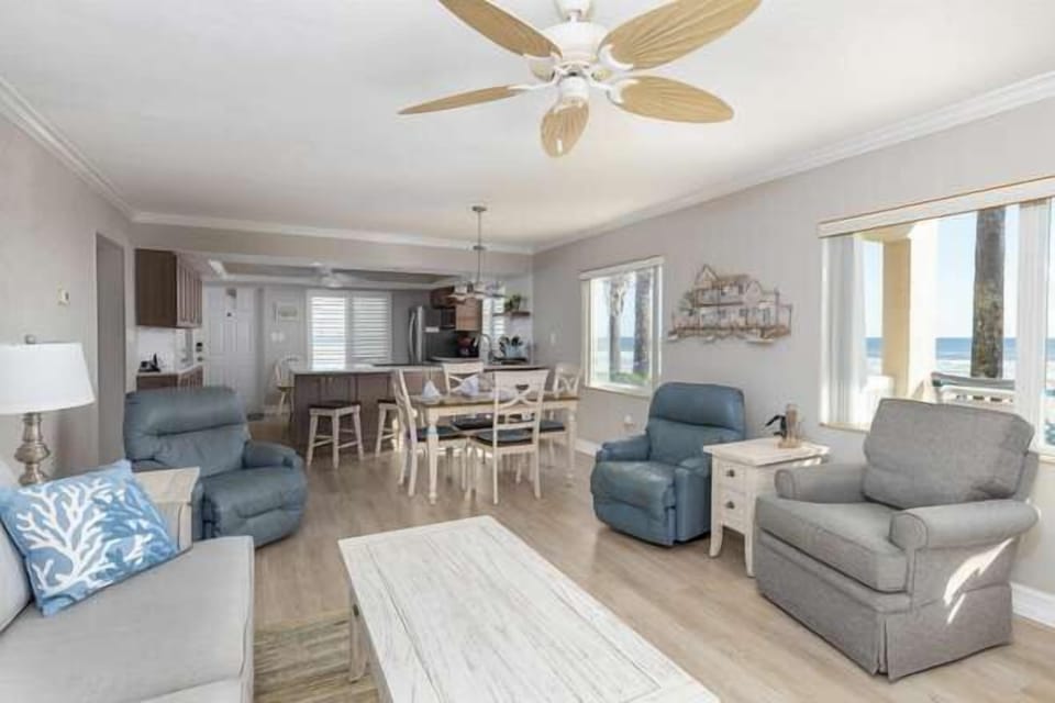 Open-concept beachside living with plush seating, dining for six, and large windows showcasing ocean views—perfect for relaxing after a day in the sun and surf.