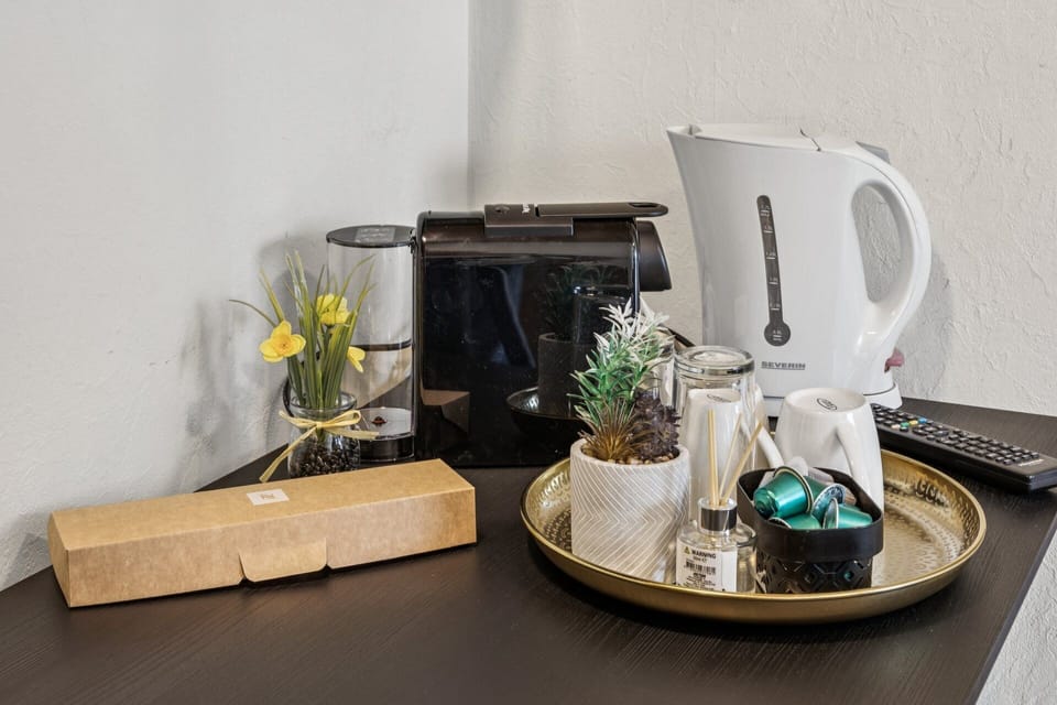 Kaffeestation mit Kapselmaschine, Wasserkocher, Tassen, Gläsern und Kapseln auf goldenem Tablett – praktisches Getränke‑Set für die Ferienwohnung.