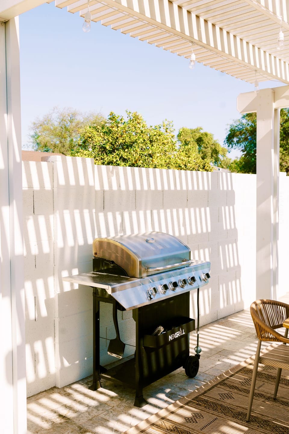 Shaded pergola patio with gas grill and cozy seating—BBQ ready