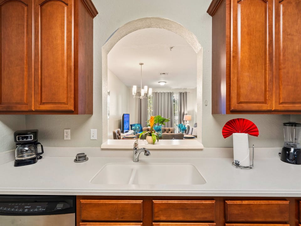 Bright kitchen with warm wood cabinets and an arched pass-through-brew coffee, blend smoothies, and stay connected to the living room and dining area.