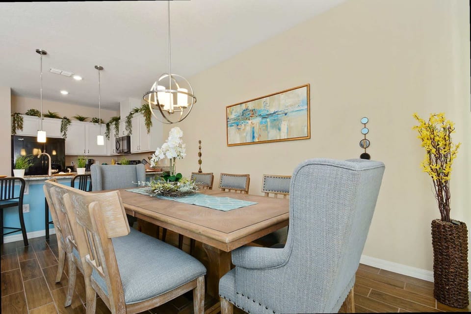 Cook with company in this open kitchen/dining blend, featuring white cabinets, granite counters & black appliances. Modern pendants hang above a cozy table perfect for family meals or game nights.
