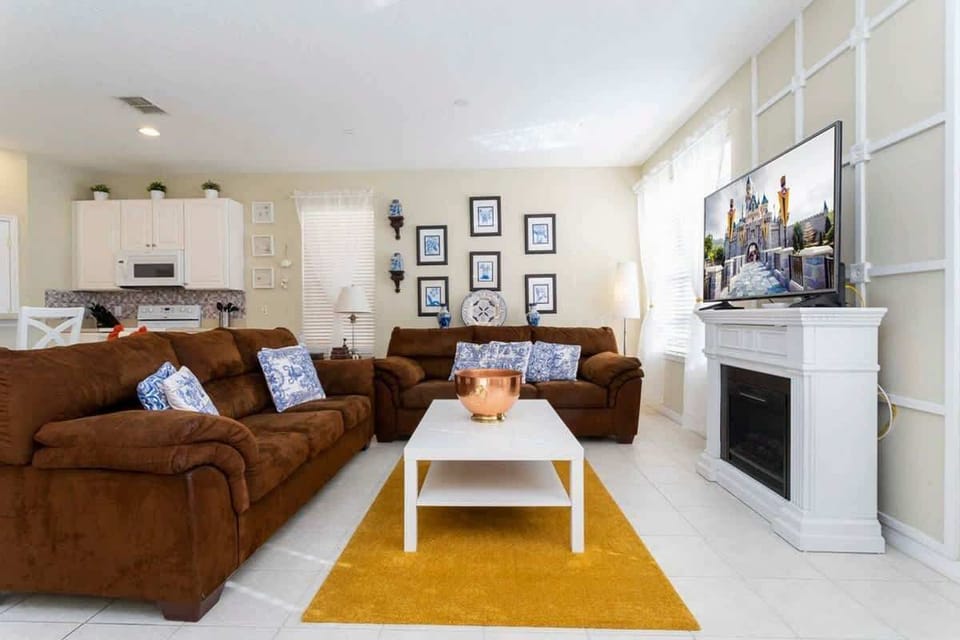 Cozy living room with two plush brown sofas, stylish blue and white pillows, a white coffee table, and a bright yellow rug. Perfect for relaxing and entertaining!