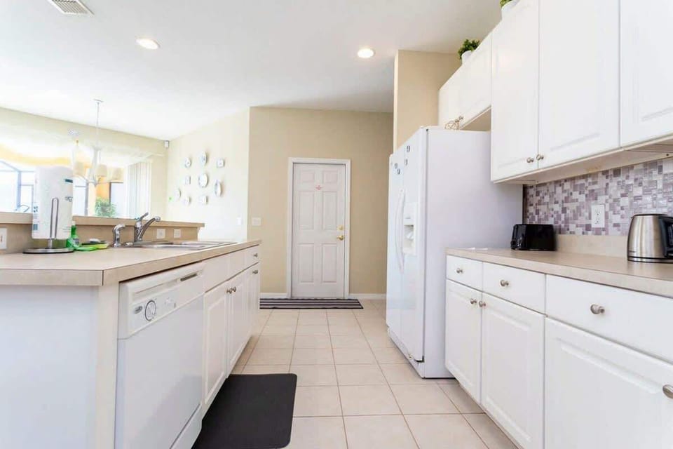 Clean and bright kitchen with white cabinets, modern appliances, and a mosaic backsplash. Perfect for preparing meals in a calm, inviting space!