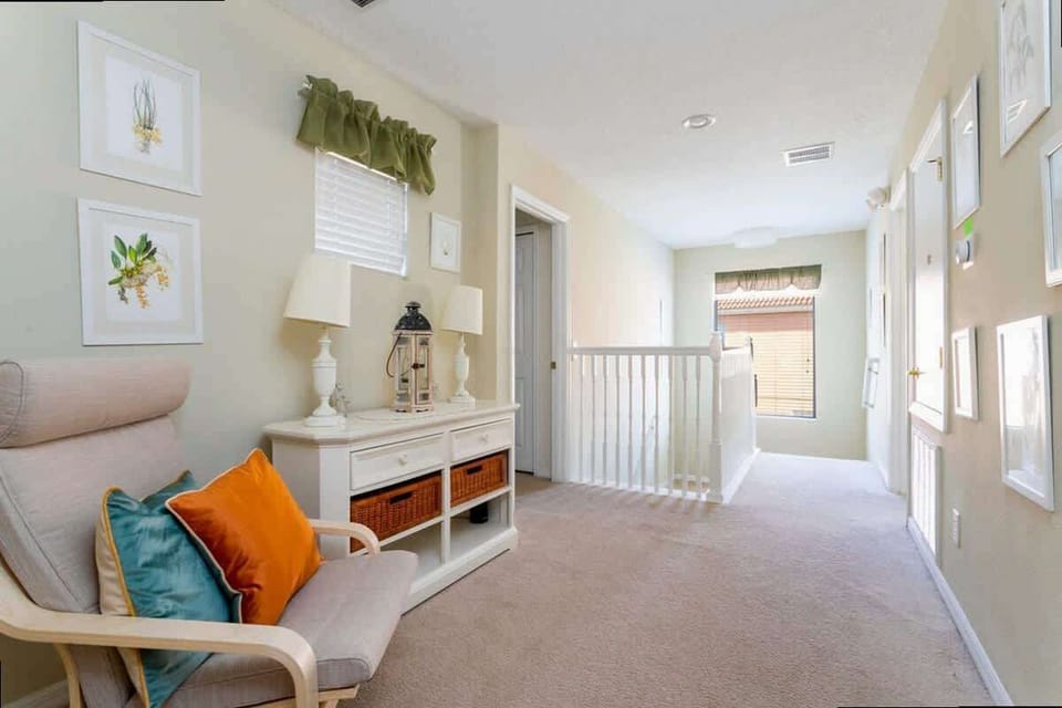 Cozy upstairs landing with a charming armchair, colorful pillows, and a gallery wall of framed art. Bright and inviting space for relaxing or reading!