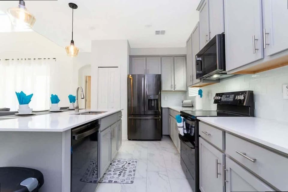 Prepare delicious feasts in this fully equipped modern kitchen, featuring black stainless appliances and crisp gray cabinets for a stylish touch.