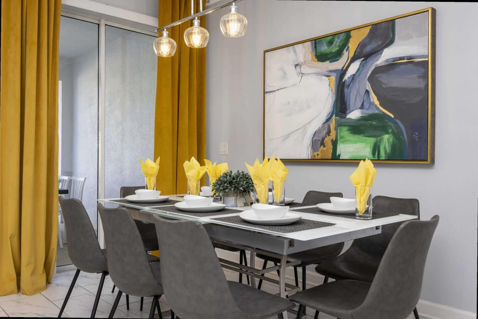Dine in style with a contemporary dining room featuring chic gray chairs, elegant lighting, and vibrant yellow accents for a welcoming meal-time ambiance!