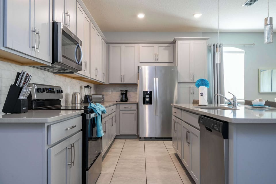 Chef-friendly kitchen with stainless appliances, roomy fridge, dishwasher, and shaker cabinets-plus coffee maker and blender for easy meals at home.