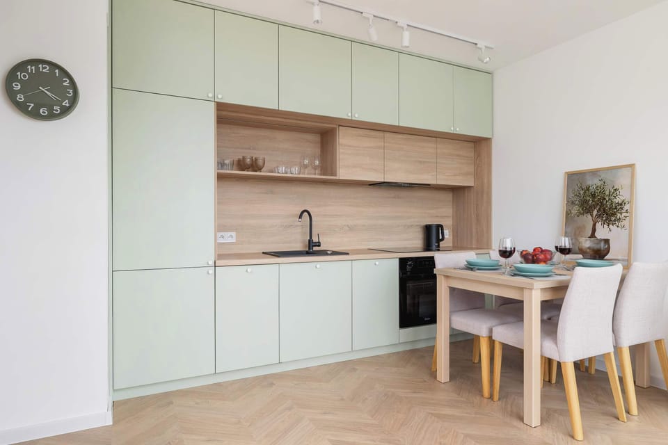A stylish kitchen with mint green cabinetry and wood accents integrated into the open-plan space.

