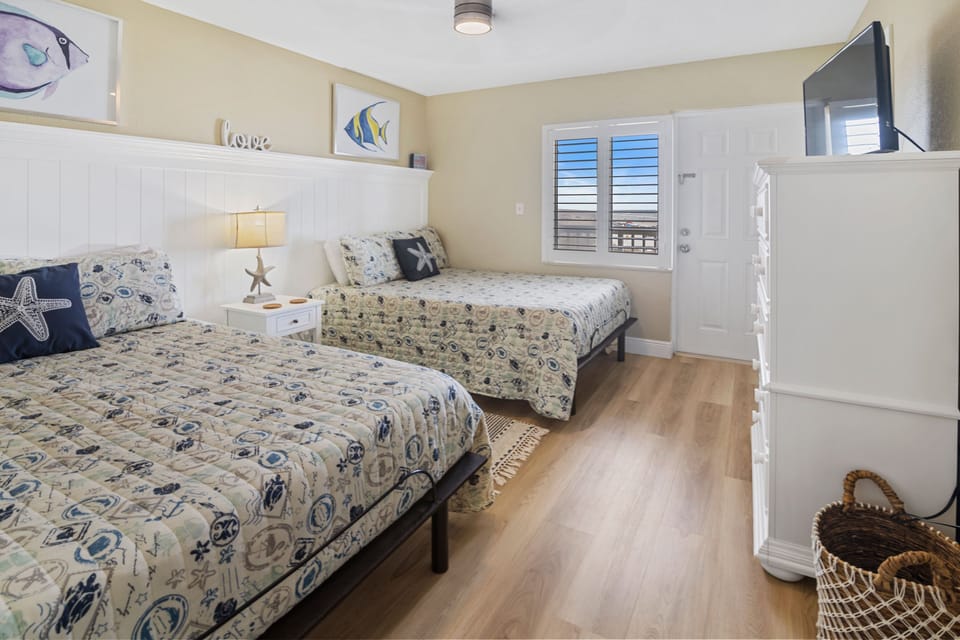 Relax in this bright beach-inspired guest room featuring two comfortable beds, nautical décor, and a flat-screen TV—perfect for unwinding after a fun-filled day by the ocean.