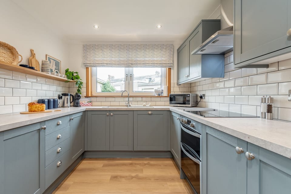 Contemporary kitchen with pale blue cabinetry, wood countertops, white subway tiles, and dual oven.